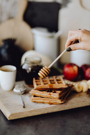 Hand layering some honey on top of a waffleの素材