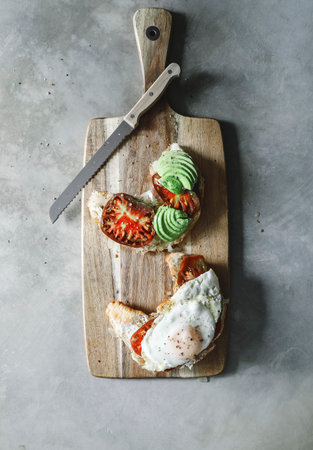 Croissant with tomatoes and avocado on a chopping boardの素材