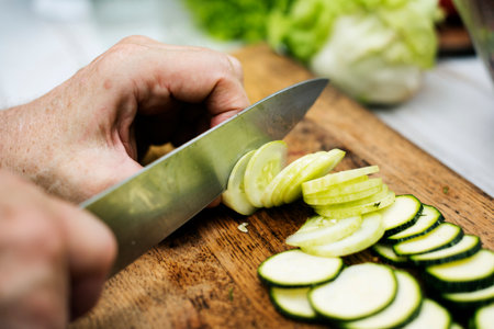 Closeup of hand with knife cutting cucumberの素材