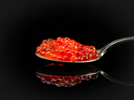 Red caviar in a spoon close-up. Fine food. Salmon ROE on a black background