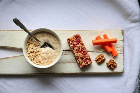 A healthy and balanced breakfast spread featuring a bowl of oatmeal, a granola bar, carrot sticks,...