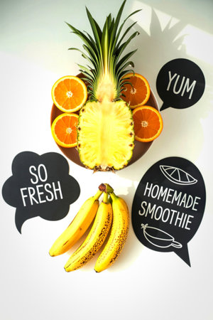 A vibrant arrangement of fresh pineapple, sliced oranges, and bananas, with speech bubbles proclaiming 'Yum', 'So Fresh', and 'Homemade Smoothie'.の写真素材