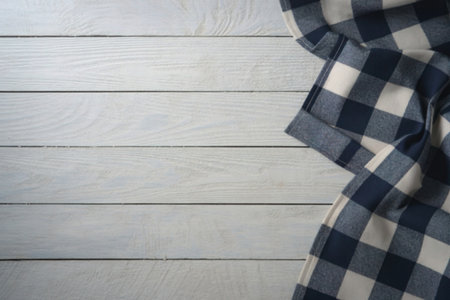 A textured white wooden surface is partially covered by a dark plaid fabric, creating a rustic and...
