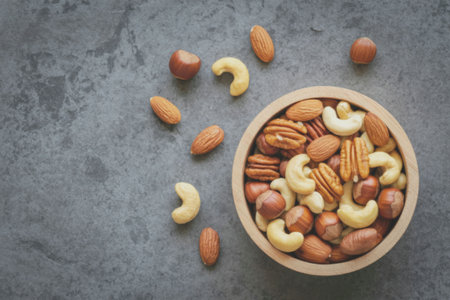 A wooden bowl filled with a variety of nuts, including almonds, cashews, hazelnuts, and pecans,...