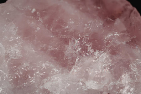 This image shows a close-up view of a pink crystal with a rough texture and sparkling surface.