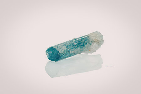 The image features a blue crystal with a rough texture, partially transparent, and lying on a...