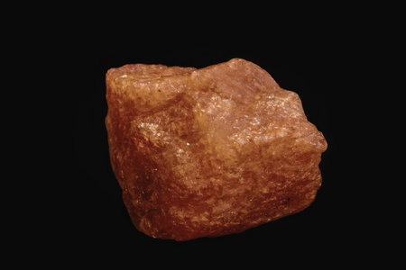 A close-up photograph of a rock with a rough texture against a black background.