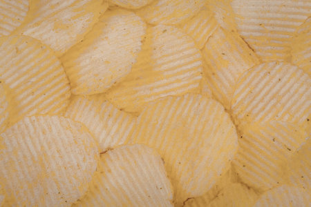 A vibrant and appetizing close-up image of golden potato chips with ridged texture.