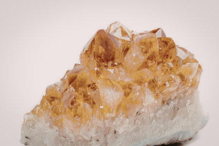 A cluster of citrine crystals on a white background, showcasing its vibrant orange color and unique...