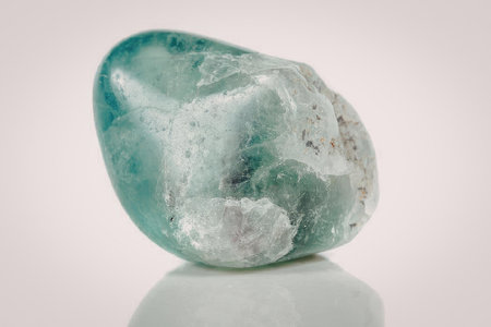 This image presents a detailed view of a polished aquamarine gemstone. The stone exhibits a...