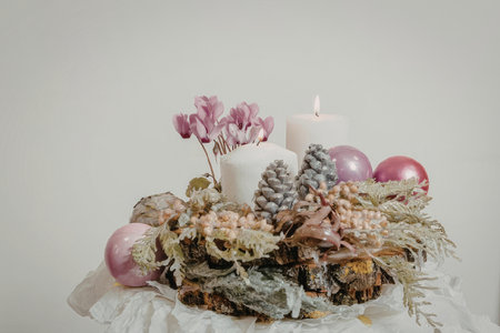 A beautifully arranged Christmas centerpiece featuring pink ornaments, pinecones, and a white candle...