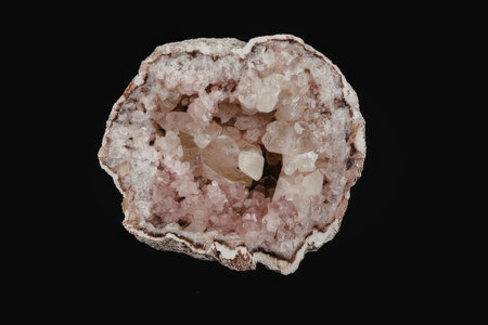 A geode with crystals on a black background, showcasing its pink and white crystalline structure.