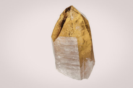 A large citrine crystal point with a golden yellow pointed top and a white base, set against a plain...