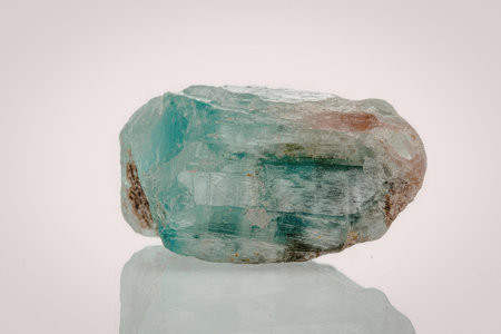 A large, rough-cut emerald gemstone with a predominantly green color and hints of red, set against a...
