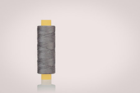 A roll of gray thread on a yellow spool