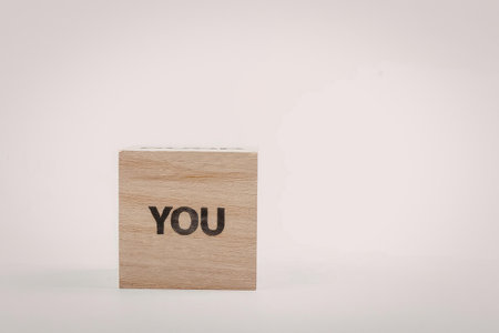 A small wooden block with the word 'you' printed on it, set against a plain white background.