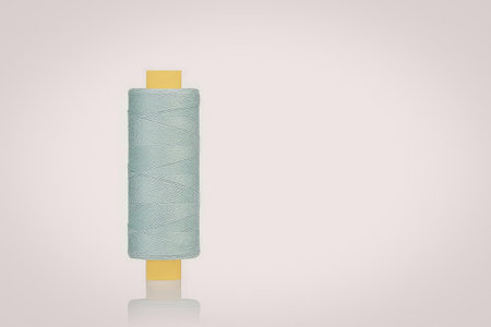 A spool of thread with a yellow core and light blue thread wrapped around it.の写真素材