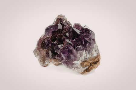 A purple amethyst crystal cluster on a rock, showcasing its natural crystalline structure.