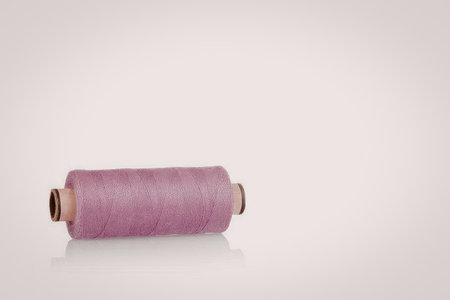 A spool of pink thread on a white background