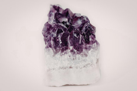 A close-up image of a purple amethyst geode cluster with a crystalline structure, set against a...