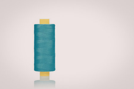 A blue and yellow spool of thread on a white background