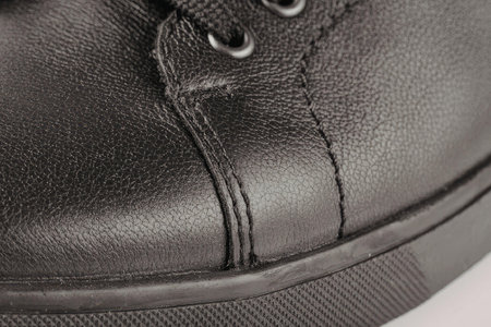 A close-up view of a black leather shoe, showcasing its texture and stitching.
