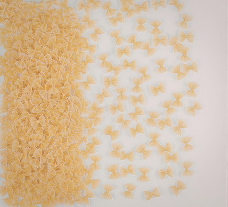 An image of golden butterfly shaped pasta arranged in a visually appealing manner on a white...