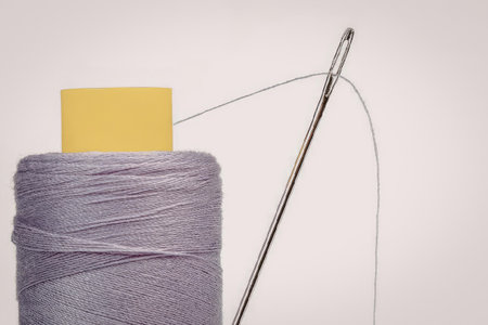 A spool of purple thread with a sewing needle and a yellow object