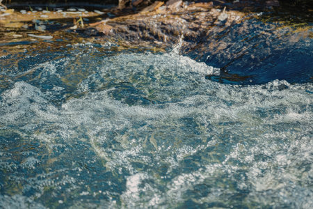 The image captures a close-up view of a water surface with ripples and reflections. The water...