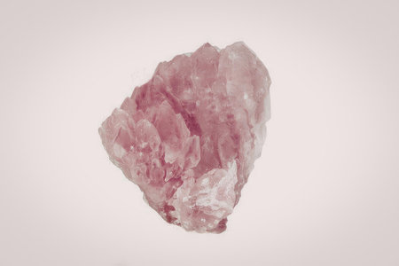A pink crystal with a rough texture and jagged edges is displayed against a white background.