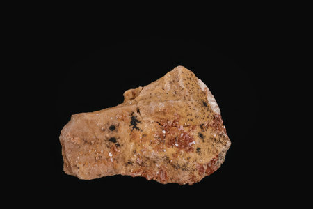 A brown and orange mineral specimen with a rough texture and vibrant coloration against a black...