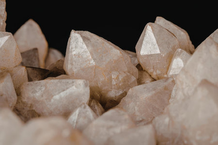 A close-up image of a cluster of quartz crystals with sharp facets and a light brown color, set...