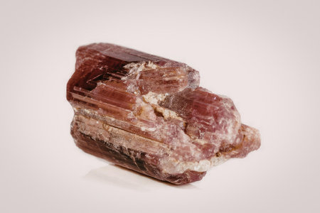 The image shows a close-up view of a red crystal with a rough texture and layered structure.