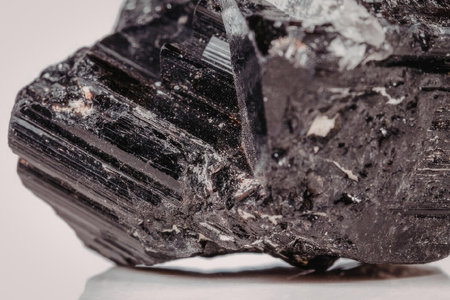 This image presents a detailed close-up of a black tourmaline crystal, showcasing its unique texture...