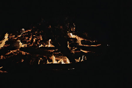 A large fire is burning brightly in the dark, with flames rising high into the air.