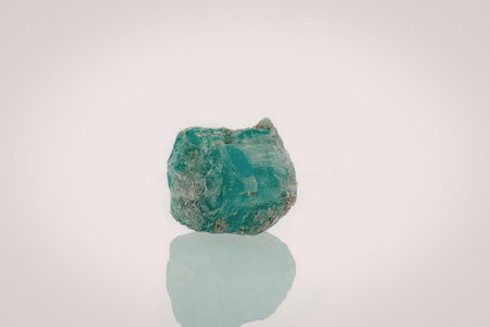 A vibrant green rough emerald gemstone with a natural, uncut surface, showcasing its unique texture...