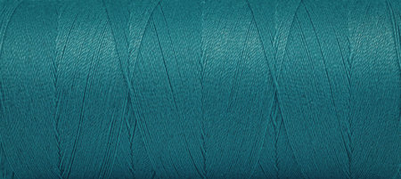 A close-up image of a spool of teal thread on a white background.