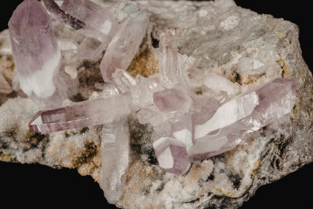 A close-up photograph of a cluster of amethyst crystals embedded in a rock, showcasing their purple...