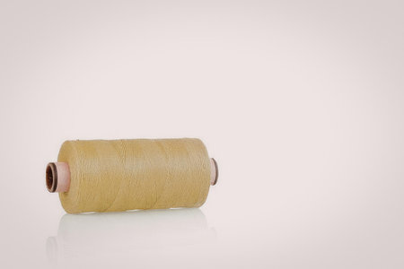 A spool of yellow thread on a white backgroundの写真素材