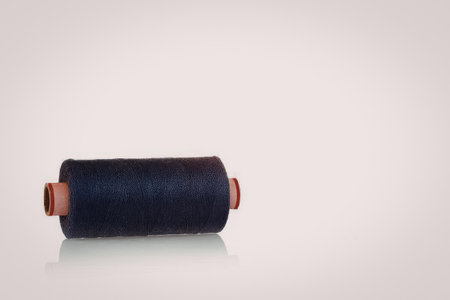 A spool of blue thread with orange ends on a white background