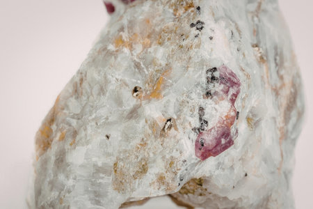 A close-up image of a rough ruby rock with a predominantly white and gray color scheme, featuring...