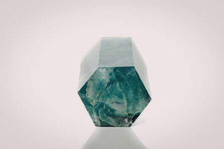 A large, faceted emerald gemstone on display against a white background. The gemstone has a unique,...