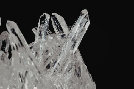 A close-up view of a crystal formation with sharp, clear, and transparent structures against a solid...