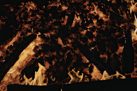 A close-up view of a fierce fire with flames in shades of orange and yellow, set against a dark...