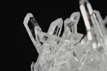 A close-up view of crystal formations with sharp, transparent structures against a black background.