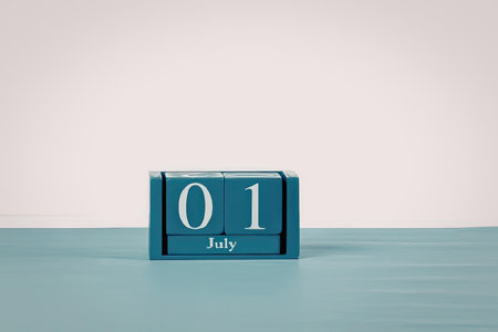 A blue calendar block with the date 01 July displayed prominently on a light blue surface against a...