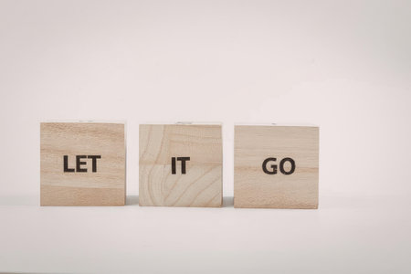 Three wooden blocks with the words 'let', 'it', and 'go' on them, symbolizing the act of releasing...
