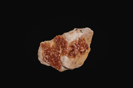 A close-up photograph of a rock formation with vibrant red crystals on a black background