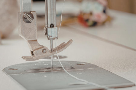 A close-up view of a sewing machine's metal parts and thread