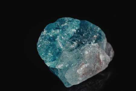A rough, uncut emerald mineral specimen with a vibrant greenish-blue color, showcasing its natural...